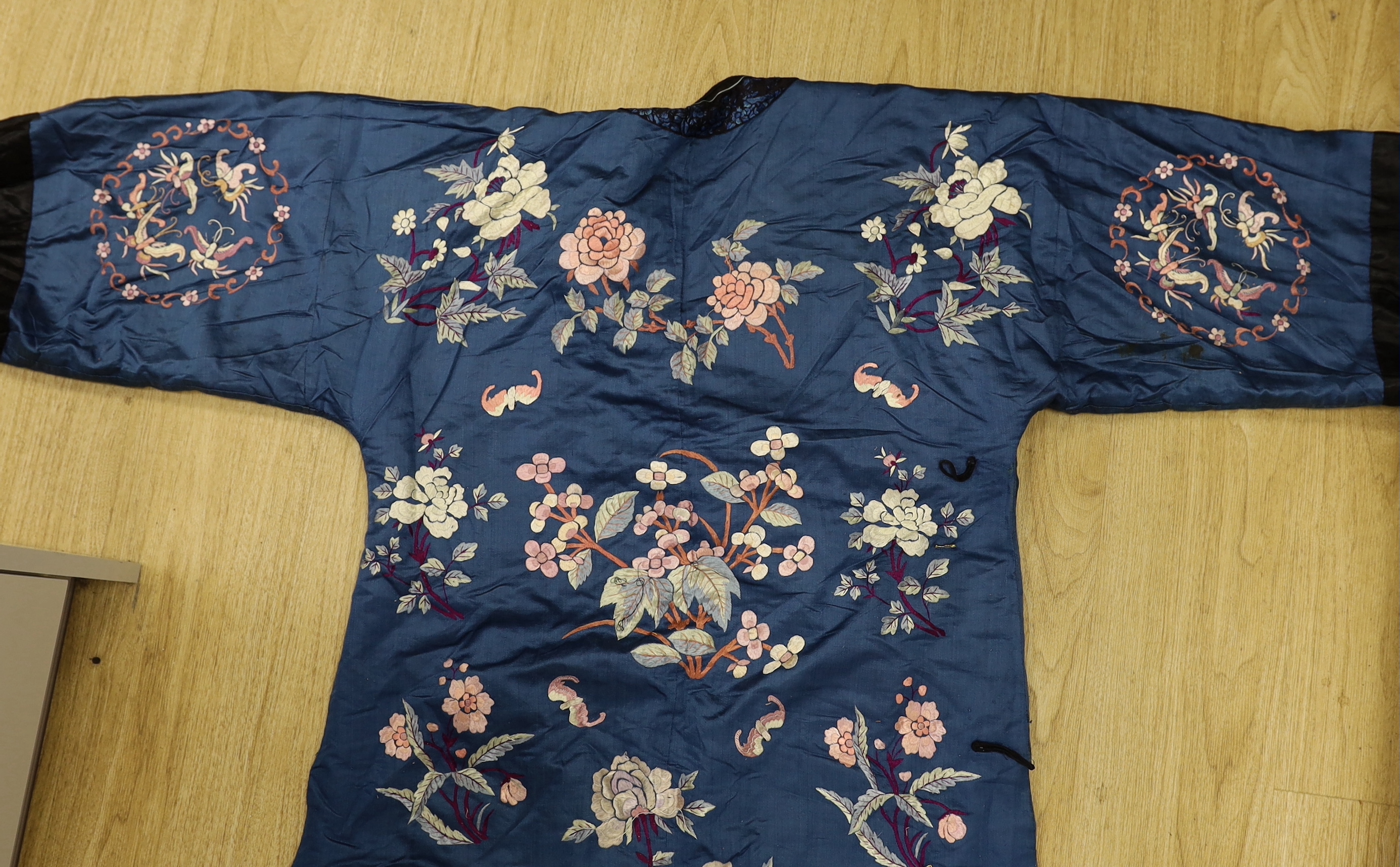 An early 20th century Chinese blue silk embroidered robe, later altered, cut and re-lined, together with various pieces of later Chinese embroidery and an earlier red silk panel with cut velvet circular motifs